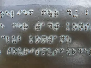 A crop of Braille written on a metallic surface at a machine shop for the visually impaired.