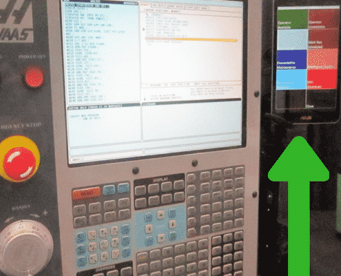A tablet with the color-coded Touch HMI software running is set up next to a Haas CNC controller.