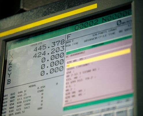 A close up of a CNC controller screen, showing program code and other data being drip fed.