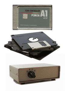 An AVM A1 PCMCIA ISDN-Controller, a stack of floppy disks, and a switch box; these are examples of legacy technology that SFA can help upgrade or replace.