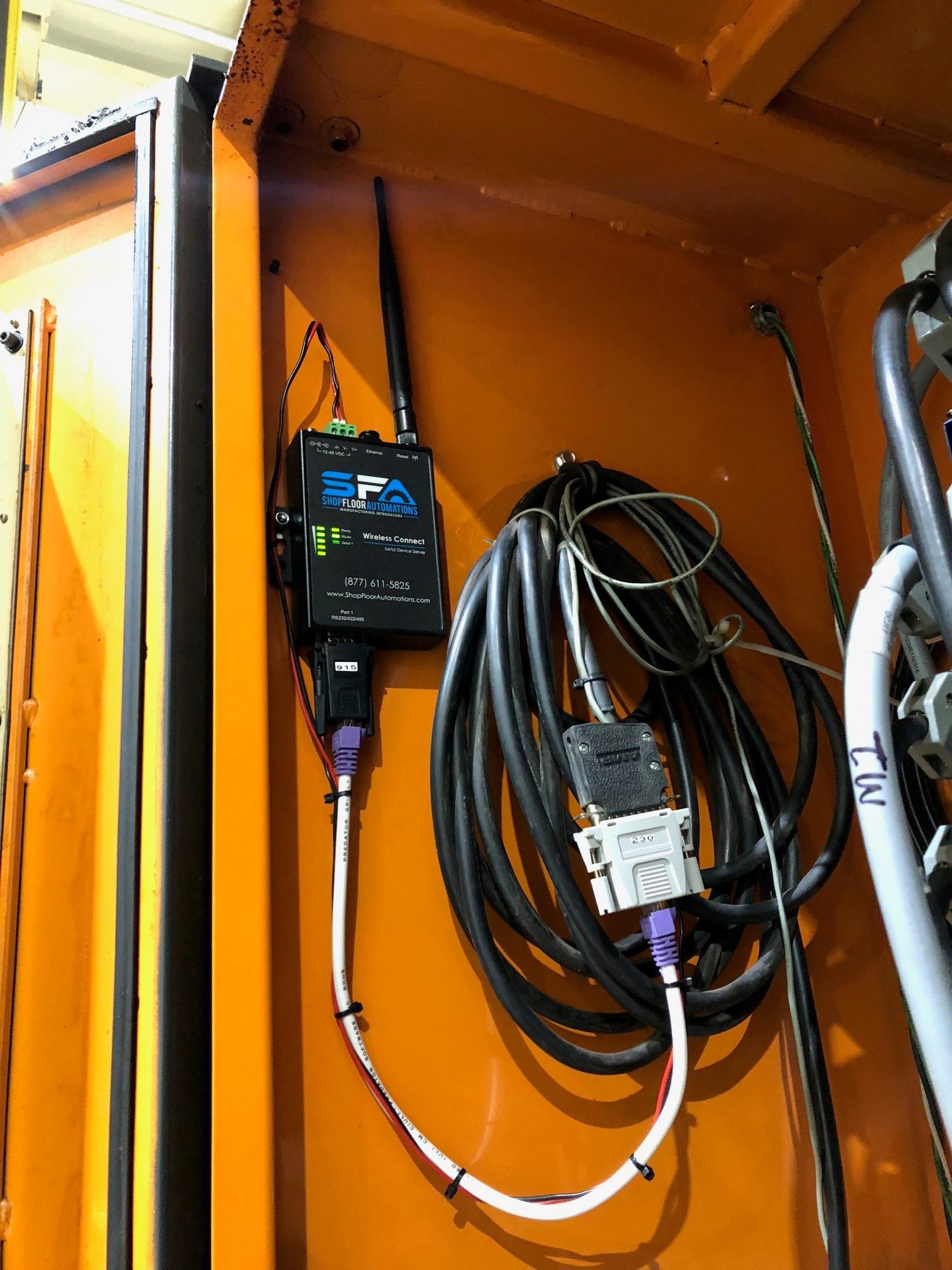 A 1-Port Wireless Connect is mounted to the inside of an orange CNC machine.