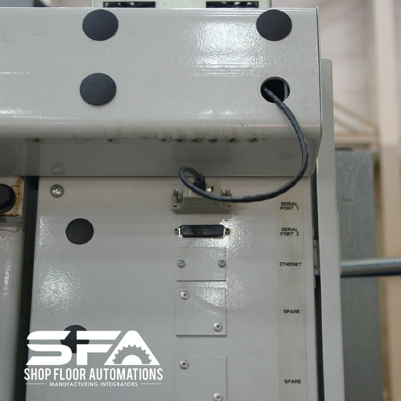 A CNC machine with a serial cable leading from Serial Port 1 to a USB Connect installed inside the machine.