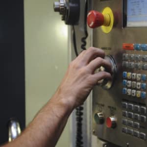 A machine operator turns the knob on a CNC controller.