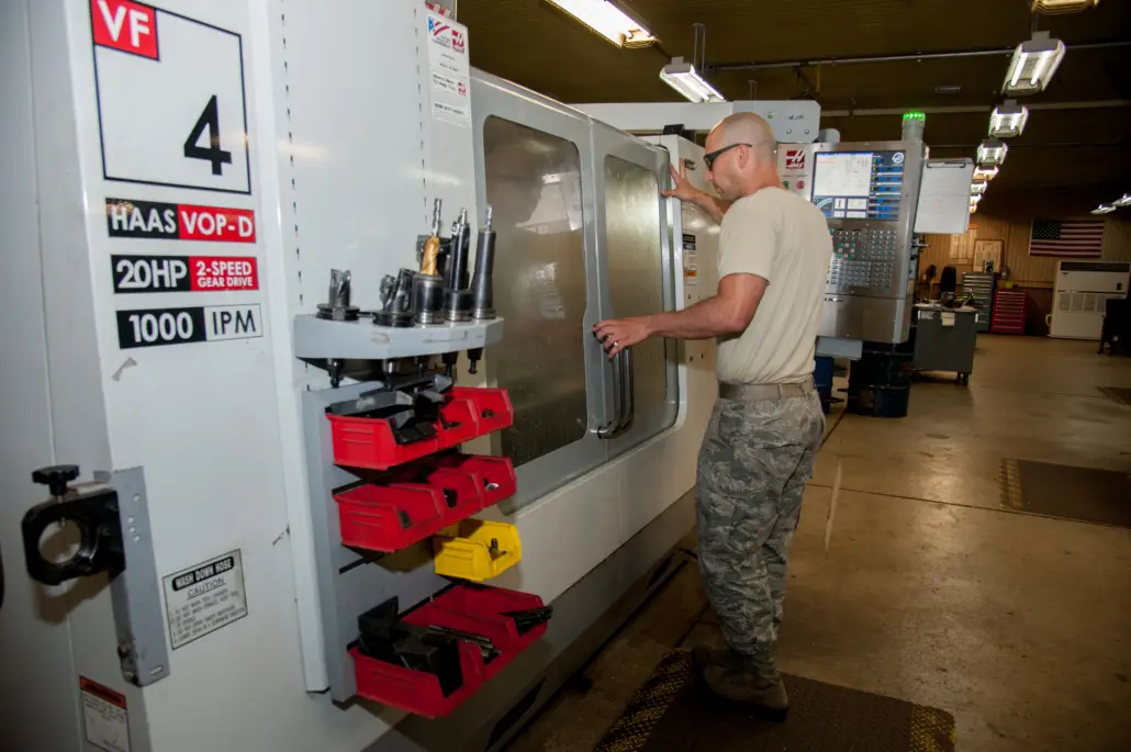 A CNC tech on the shop floor working with a Haas VF4 VOP-D CNC machine with automated data collection and revision control.