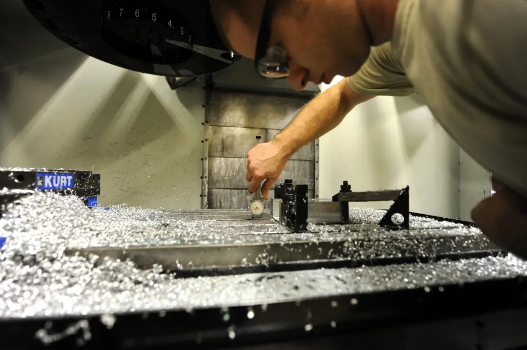 An engineer on the shop floor assessing a machine, which was visibly just in use as shown by the excess of metal shavings.