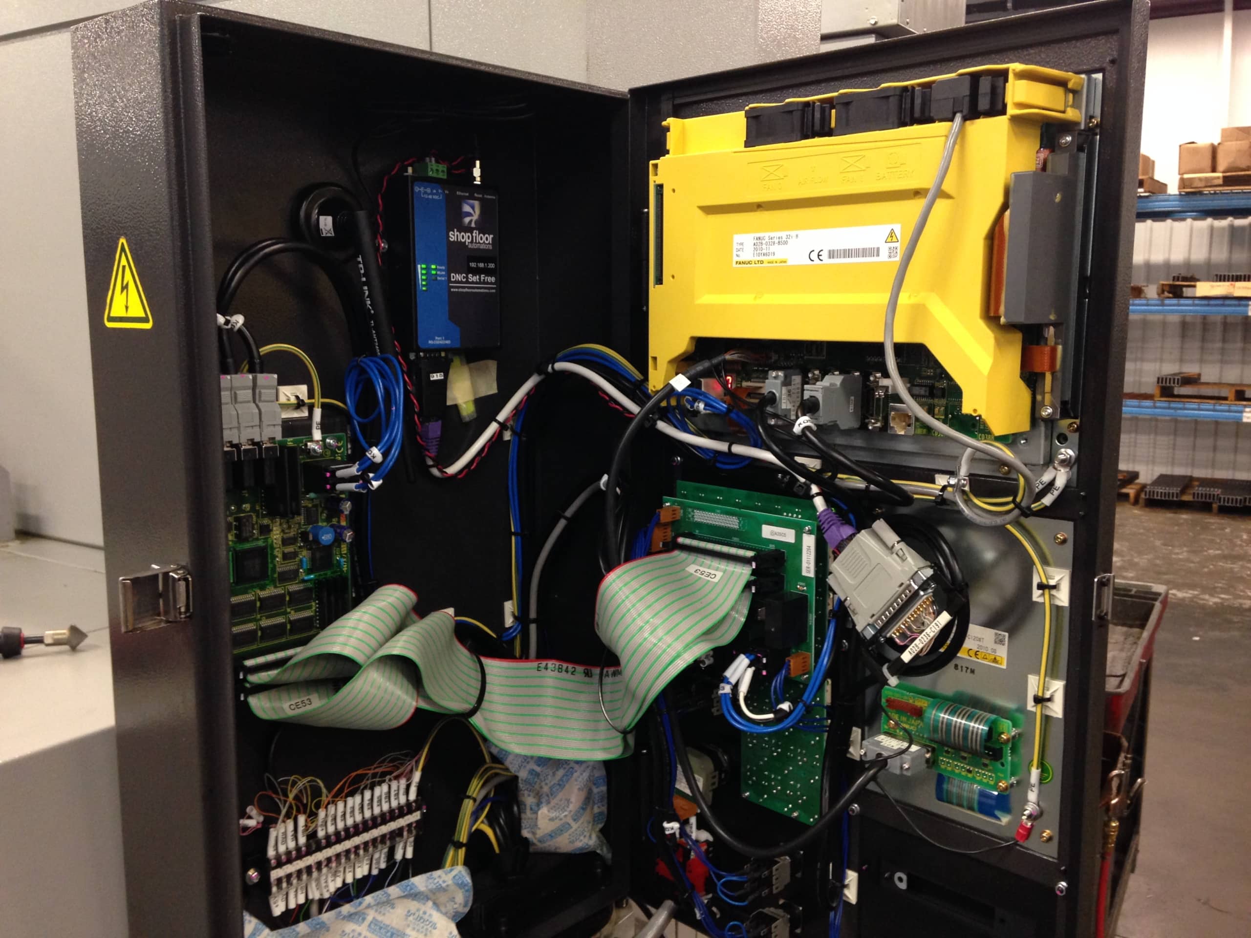 The door of a Fanuc CNC machine is opened to show that a Wi-fi Connect unit is mounted inside, adding a wireless DNC network.
