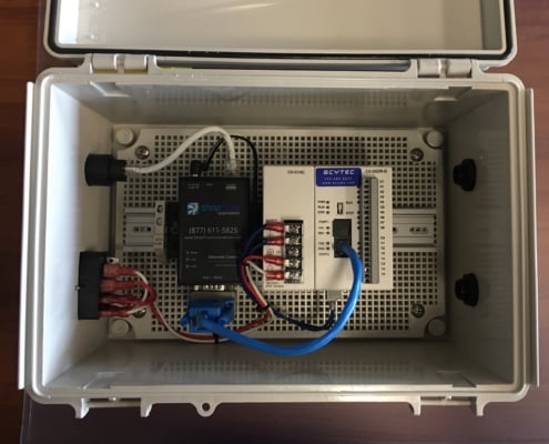 A 1-Port Wired Ethernet Connect is wired to a Scytec Status Relay Controller to collect data from the machine they're connected to. Both of them are in an enclosure which is opened for the photo.