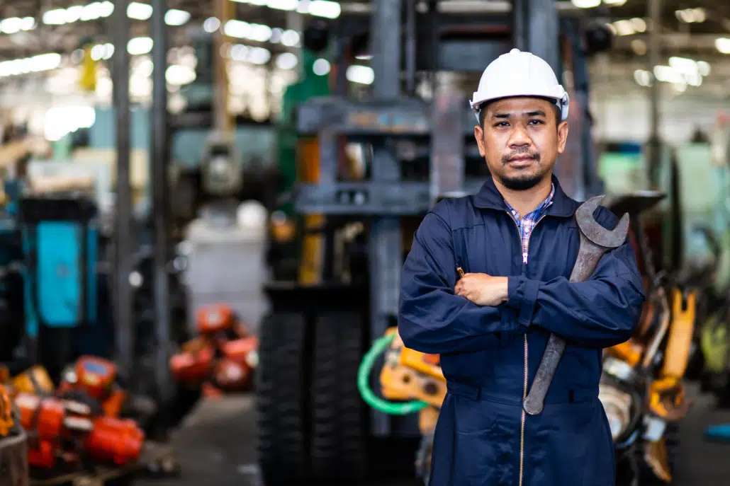 A machinist stands tall in his machine shop after a hard day of work.